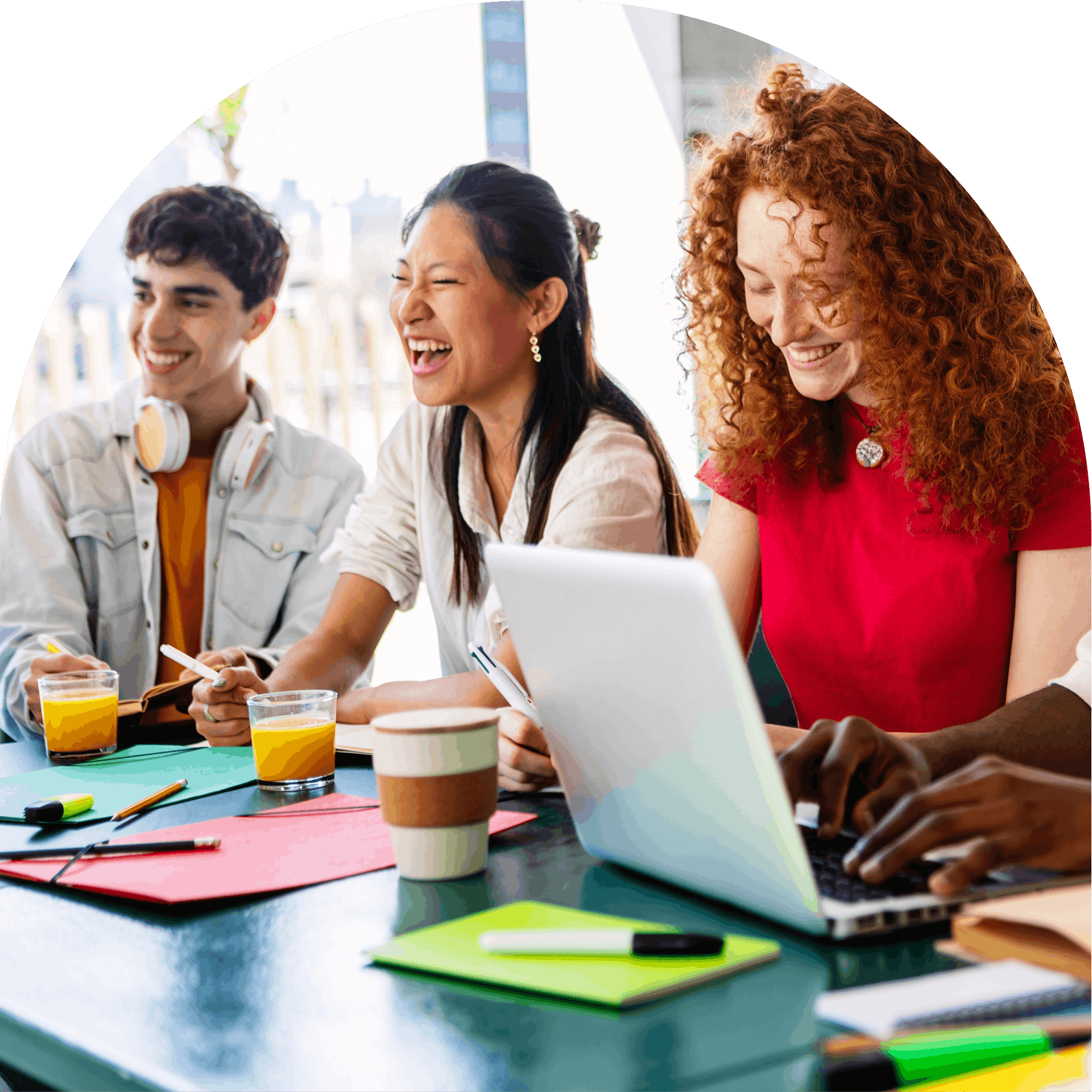Three diverse colleagues collaborating and laughing at a work table